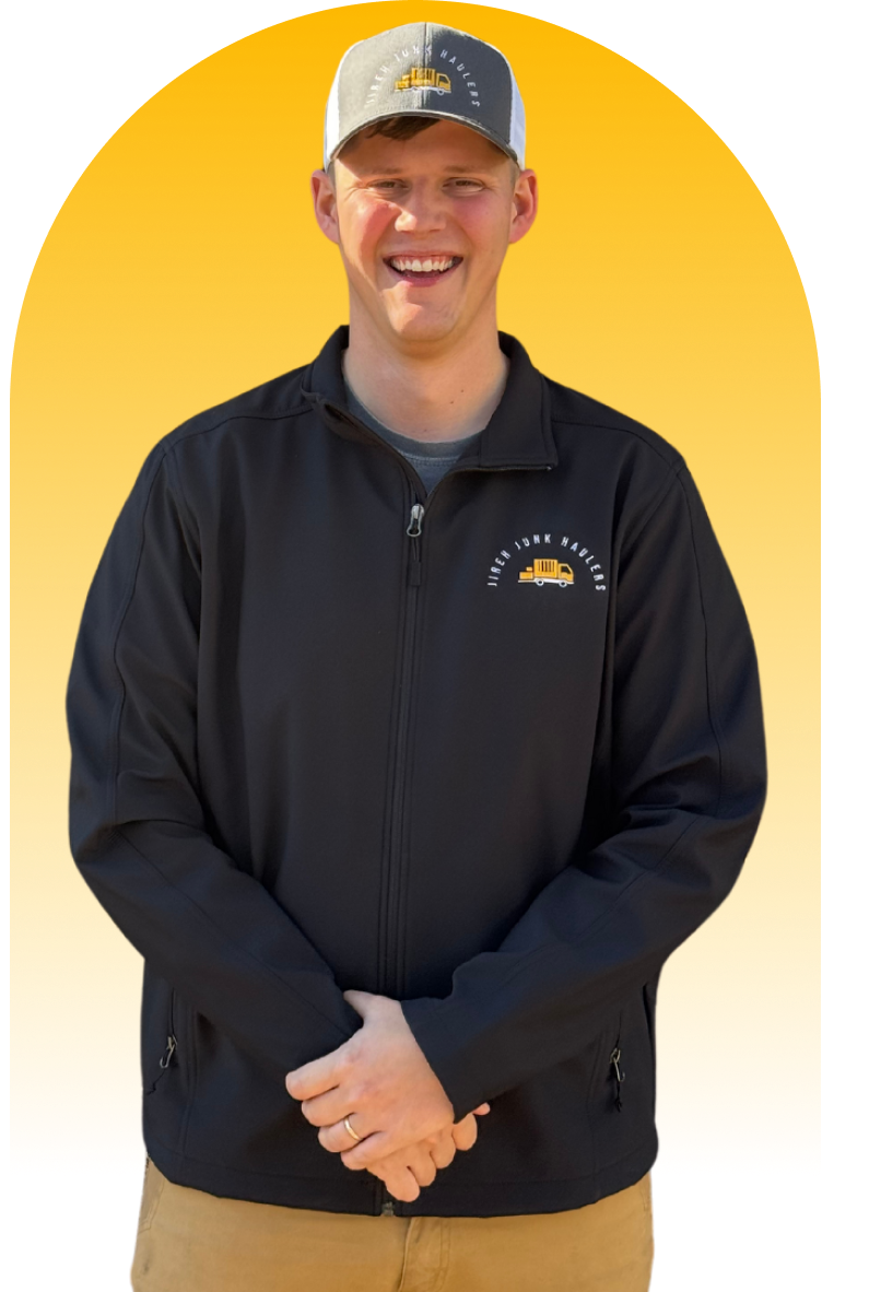 The image shows a family of four: a man, a woman, a young boy, and a baby, likely associated with Jireh Junk Haulers in Banaybanay, Davao Region, Philippines, as they are all wearing shirts with a logo featuring a truck and the text "Jireh Junk Haulers". The family is smiling and posing for a photo against a blurred outdoor background with a yellow arched overlay.